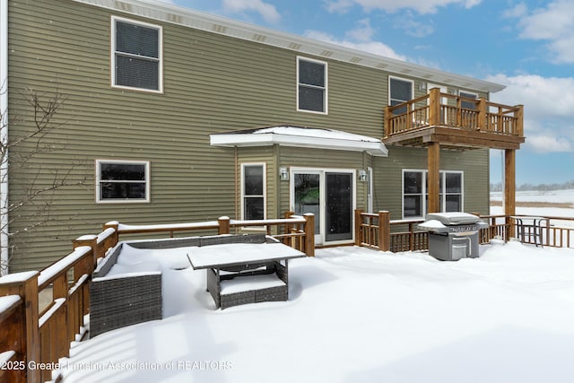 snow covered rear of property with a balcony