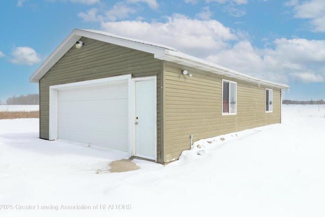 snow covered garage featuring a detached garage