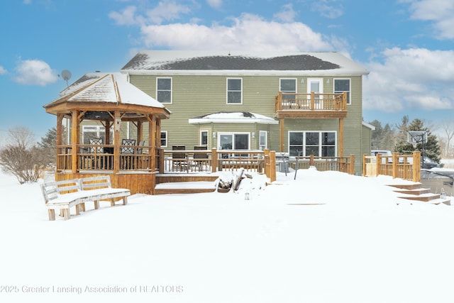 snow covered back of property featuring a balcony and a gazebo