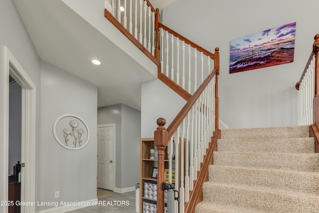 staircase with a towering ceiling, baseboards, wood finished floors, and recessed lighting