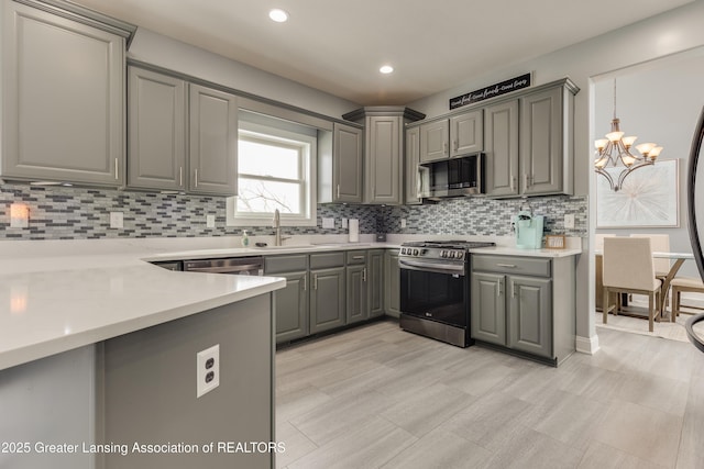 kitchen with appliances with stainless steel finishes, gray cabinets, and light countertops