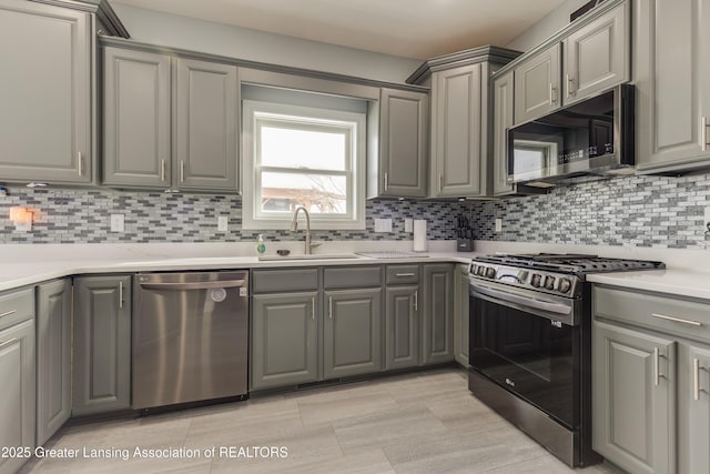 kitchen featuring light countertops, appliances with stainless steel finishes, backsplash, and a sink