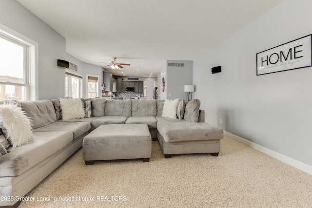 living room with ceiling fan, visible vents, and baseboards