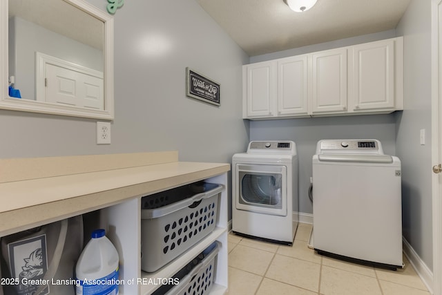 laundry room featuring light tile patterned floors, washer and clothes dryer, cabinet space, and baseboards