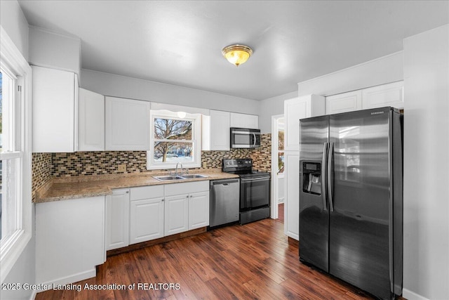 kitchen featuring dark wood finished floors, decorative backsplash, appliances with stainless steel finishes, white cabinetry, and a sink