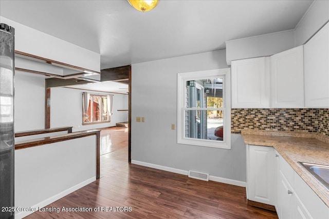 kitchen featuring visible vents, dark wood-type flooring, backsplash, and white cabinetry