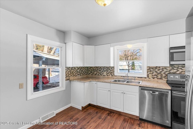 kitchen featuring stainless steel appliances, visible vents, backsplash, white cabinets, and a sink