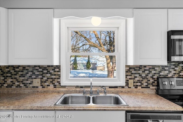 kitchen featuring white cabinets, stainless steel appliances, a sink, and light countertops