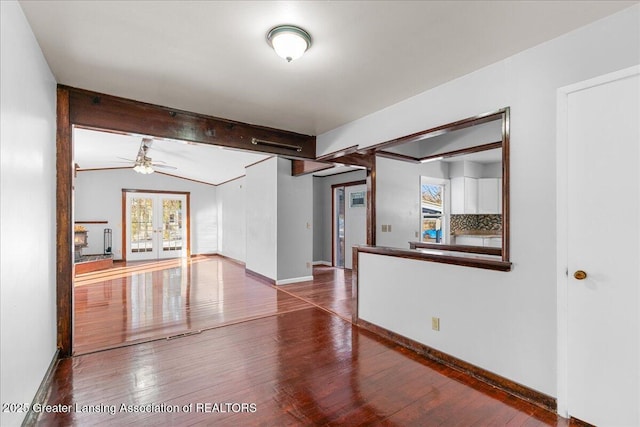 unfurnished room featuring vaulted ceiling with beams, baseboards, wood finished floors, and french doors