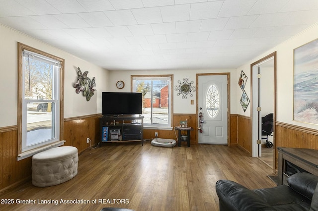 living room with a wainscoted wall, wood finished floors, and wood walls