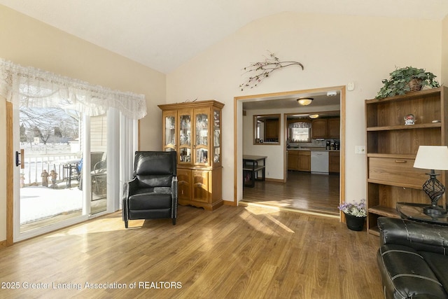 sitting room with baseboards, vaulted ceiling, and wood finished floors