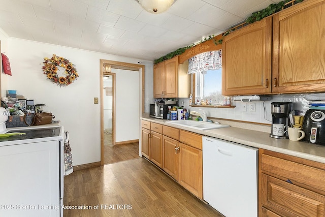 kitchen featuring light countertops, a sink, washer / dryer, light wood-type flooring, and white appliances