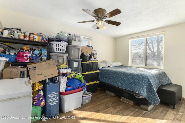 bedroom with ceiling fan, a textured ceiling, and light wood-style flooring