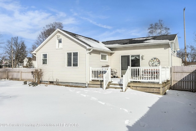 snow covered property with a deck and fence