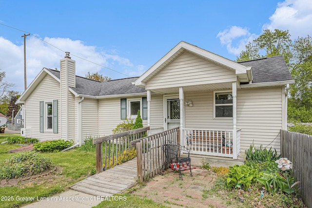 438 Union St, Grand Ledge, MI 48837 - view of front of property with a shingled roof, a porch, a chimney, and fence