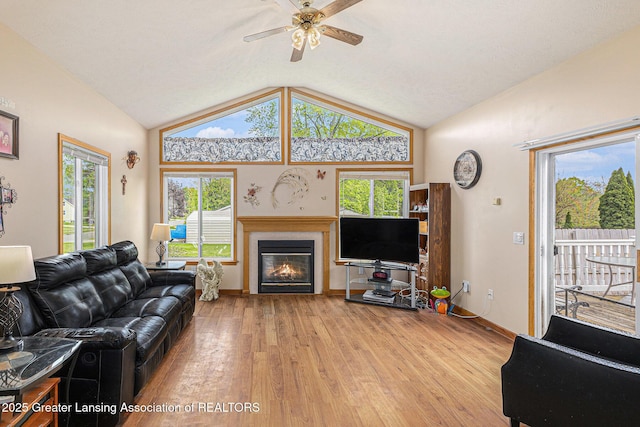 438 Union St, Grand Ledge, MI 48837 - living room featuring vaulted ceiling, light wood-style flooring, a glass covered fireplace, plenty of natural light, and a ceiling fan
