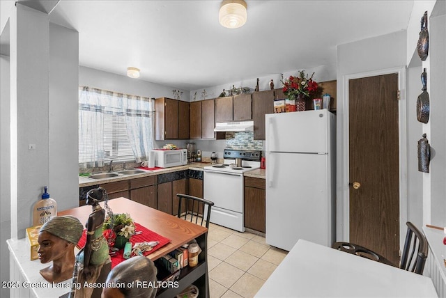 kitchen featuring dark brown cabinetry, white appliances, light countertops, under cabinet range hood, and light tile patterned flooring