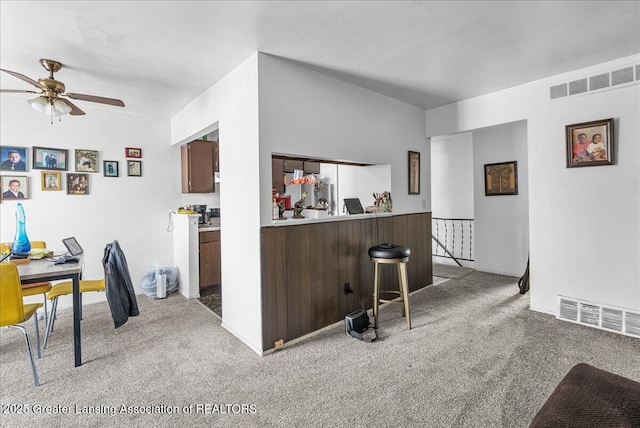 kitchen featuring light colored carpet, visible vents, and a peninsula