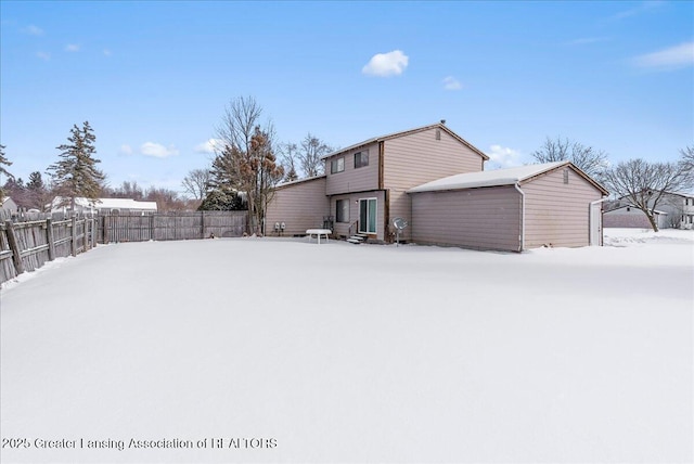 snow covered back of property featuring entry steps and fence