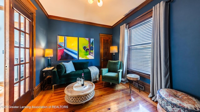 sitting room featuring crown molding, baseboards, and wood finished floors