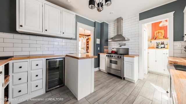 kitchen with wine cooler, stainless steel range, white cabinets, butcher block countertops, and wall chimney exhaust hood