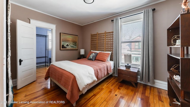 bedroom with crown molding, baseboards, and wood finished floors