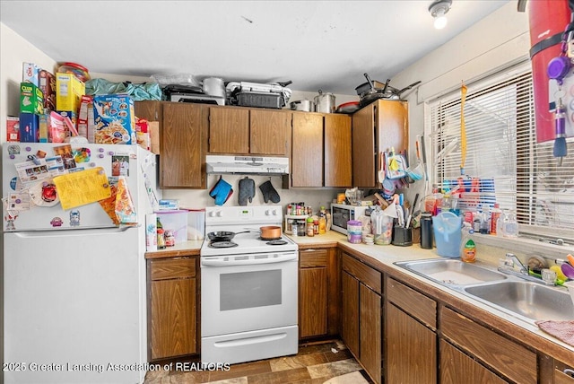 kitchen with light countertops, brown cabinetry, a sink, white appliances, and under cabinet range hood