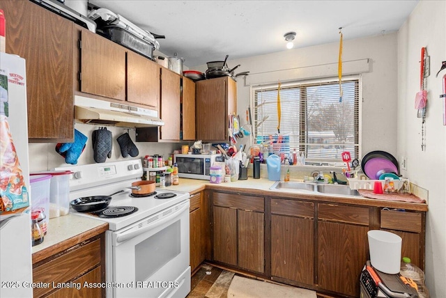 kitchen featuring light countertops, white electric range, a sink, and under cabinet range hood