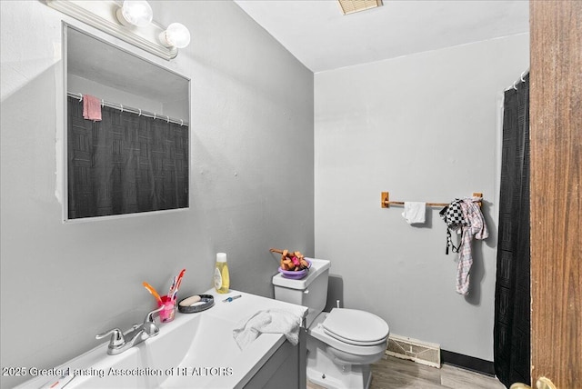 full bath with visible vents, toilet, vanity, wood finished floors, and baseboards