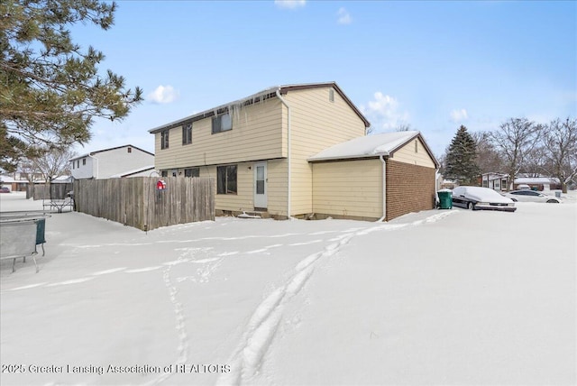 snow covered house featuring entry steps and fence