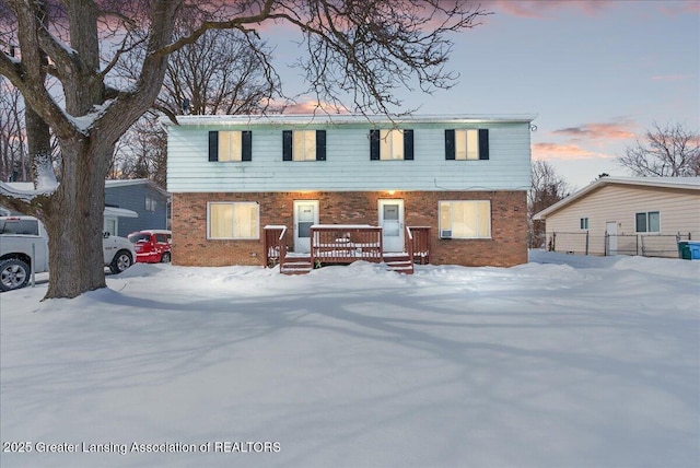 view of front facade with a wooden deck and brick siding