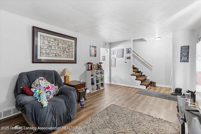 living area featuring baseboards, stairs, visible vents, and wood finished floors