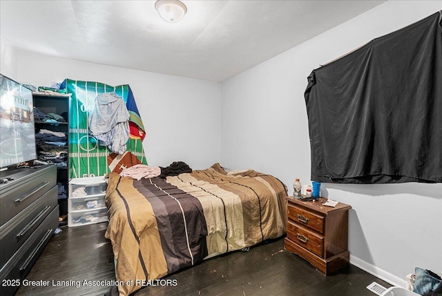 bedroom with dark wood-style floors and visible vents