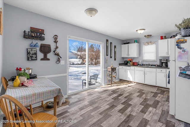 kitchen featuring a wealth of natural light, dark countertops, freestanding refrigerator, and white cabinets