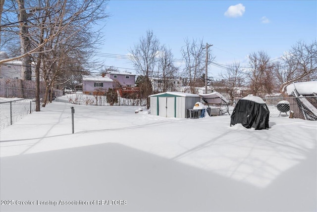 yard covered in snow with an outdoor structure, fence, and a storage unit