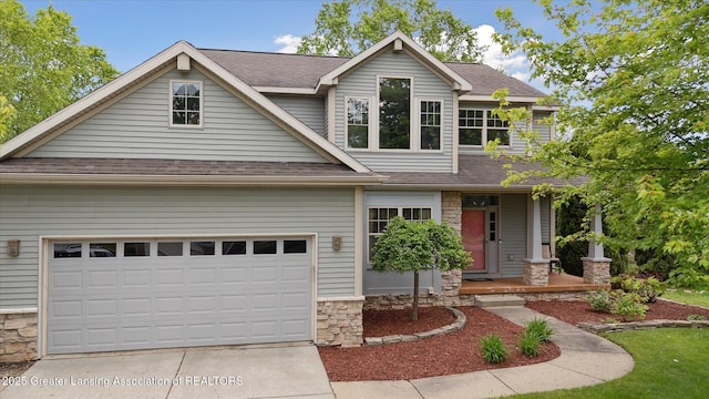 11610 Hibiscus Ln, Grand Ledge, MI 48837 - craftsman-style house with stone siding, roof with shingles, driveway, and covered porch