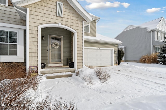 snow covered property entrance with a garage