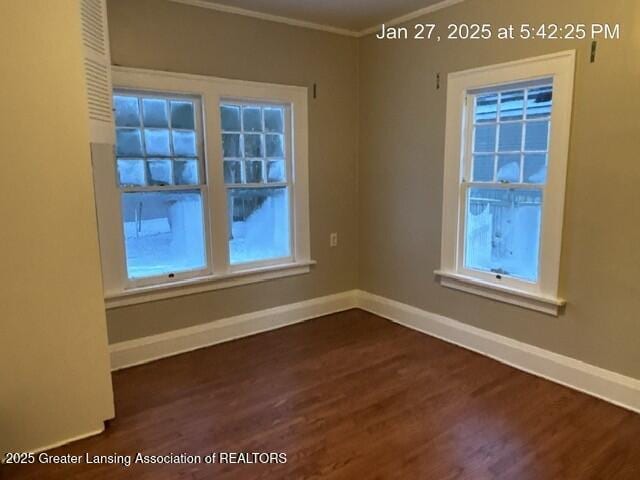 spare room with dark wood-type flooring, ornamental molding, and baseboards