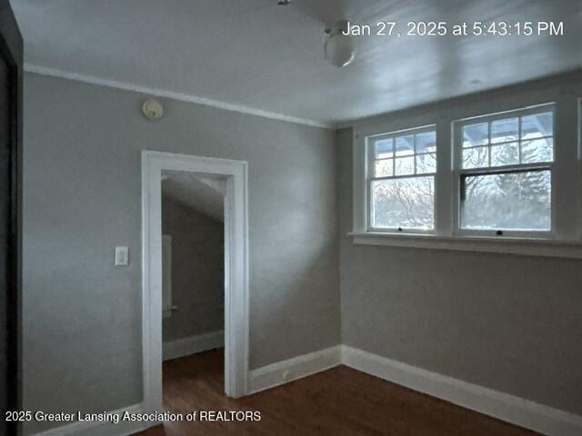 empty room with dark wood-type flooring and baseboards