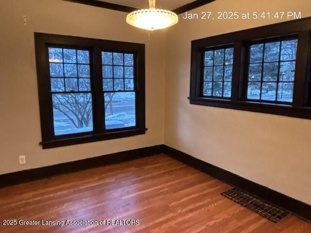 unfurnished room featuring wood finished floors, visible vents, and baseboards