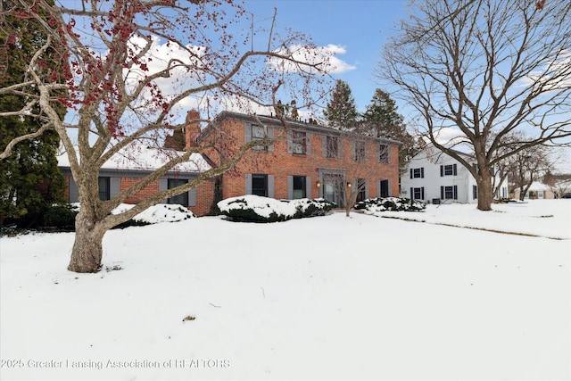 colonial home with a garage, brick siding, and a chimney