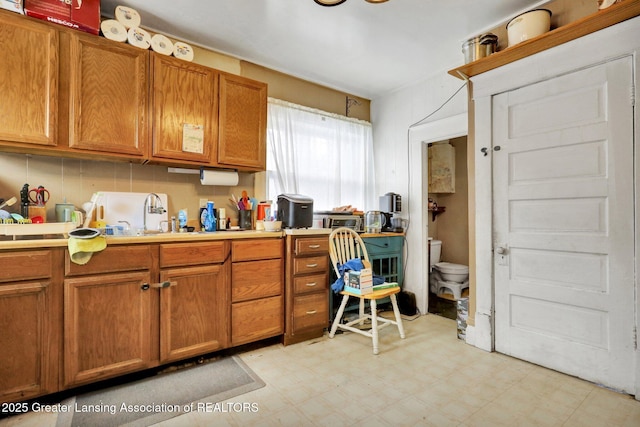 kitchen featuring light countertops, light floors, a sink, and brown cabinetry