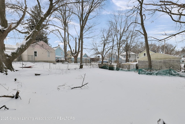 yard layered in snow featuring a residential view and fence