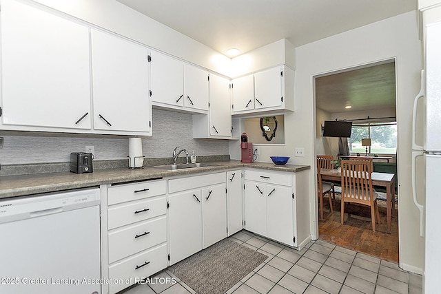 kitchen featuring light tile patterned floors, white appliances, a sink, white cabinetry, and backsplash