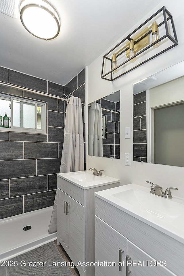 full bath featuring a sink, a shower stall, visible vents, and two vanities