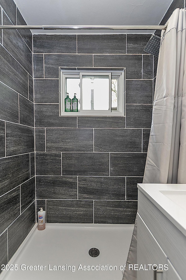 bathroom with a tile shower and vanity