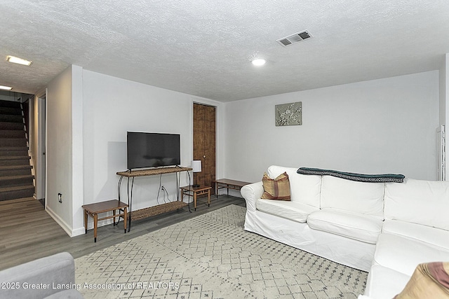 living area featuring stairs, visible vents, dark wood finished floors, and a textured ceiling