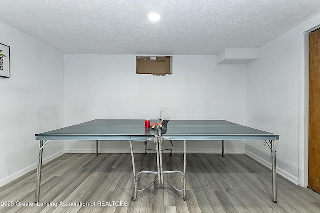 rec room with a textured ceiling, baseboards, and wood finished floors