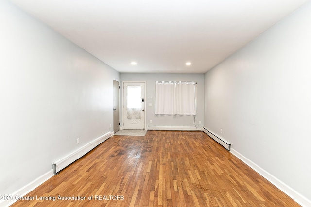 unfurnished room with a baseboard heating unit, baseboards, baseboard heating, and wood finished floors