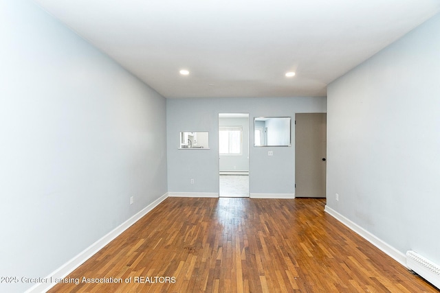 spare room featuring dark wood-type flooring, a baseboard radiator, visible vents, and baseboards